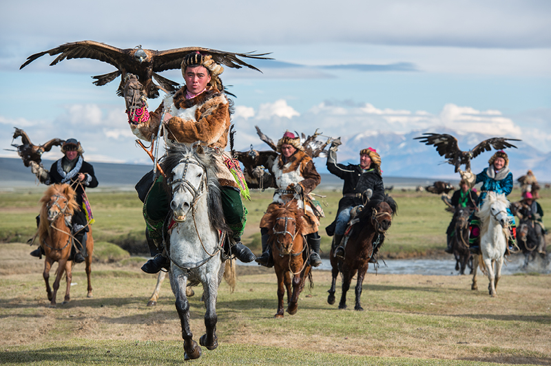 Kazakh Mongolian Cavalry Golden Eagle Hunter across the river in Altai Mountains