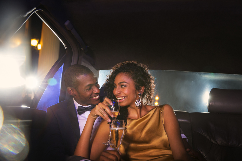 Glamorous couple in limo drinking chmapagne