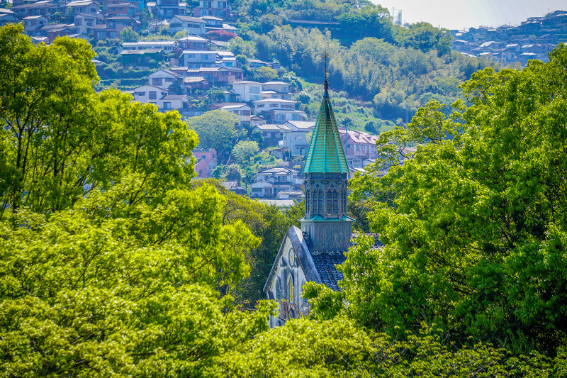 Spire of Oura Catholic church seen through green foliage of Nagasaki