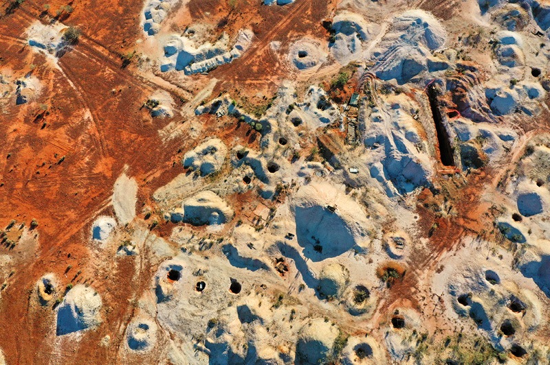 Mineshaft holes and white dirt mine tailings on red earth in White Cliffs.