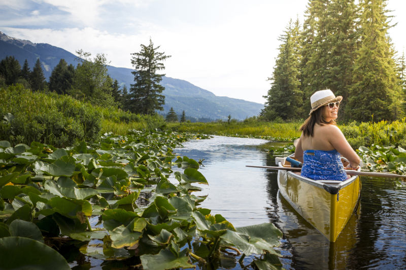 Woman looks back from canoe on River of Golden Dreams in Whistler