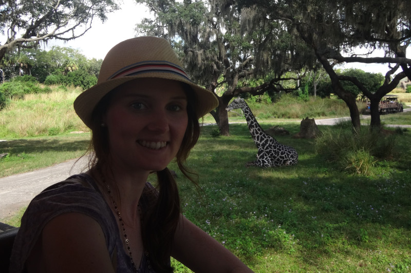 Photo of female tourist with giraffe in background