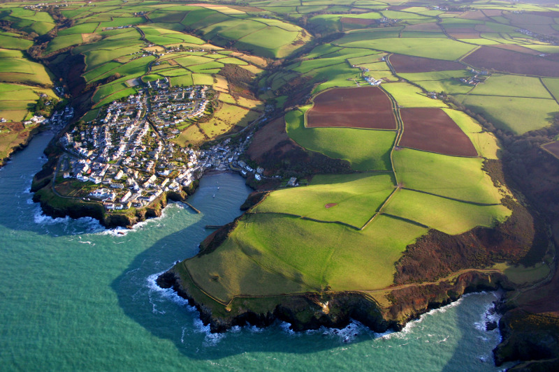 Aerial view of Cornish seaside town among green patchwork fields