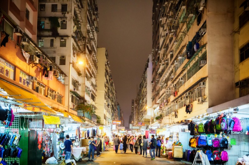 Temple Street night market with its bright lights under a canopy of apartment buildings. Image: Getty images.