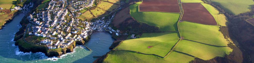 Aerial view of Cornish seaside town among green patchwork fields