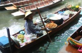 A vendor sells food from her boat in Thonburi, Bangkok