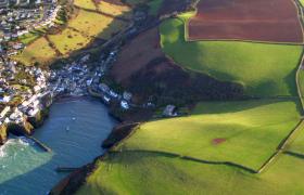 Aerial view of Cornish seaside town among green patchwork fields