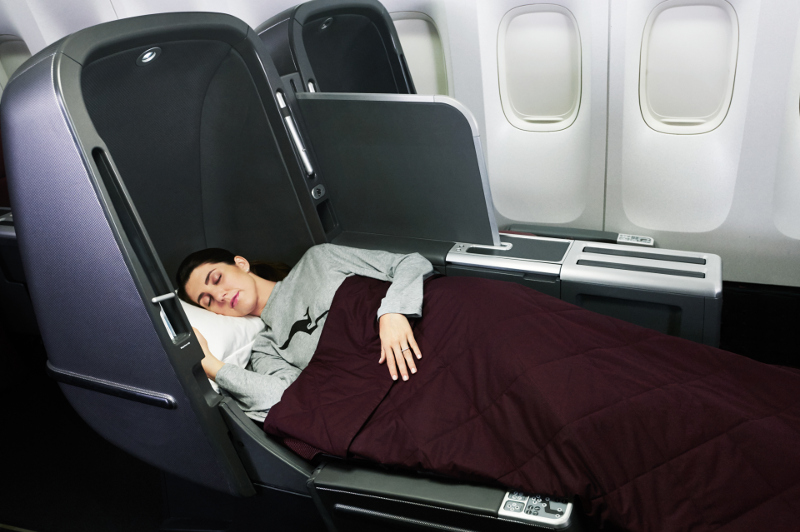 Qantas hostess hands guest a drink while inflight